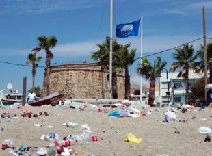 Imaxe dunha praia con bandeira azul, mais invadida polo lixo (Foto: Adega)